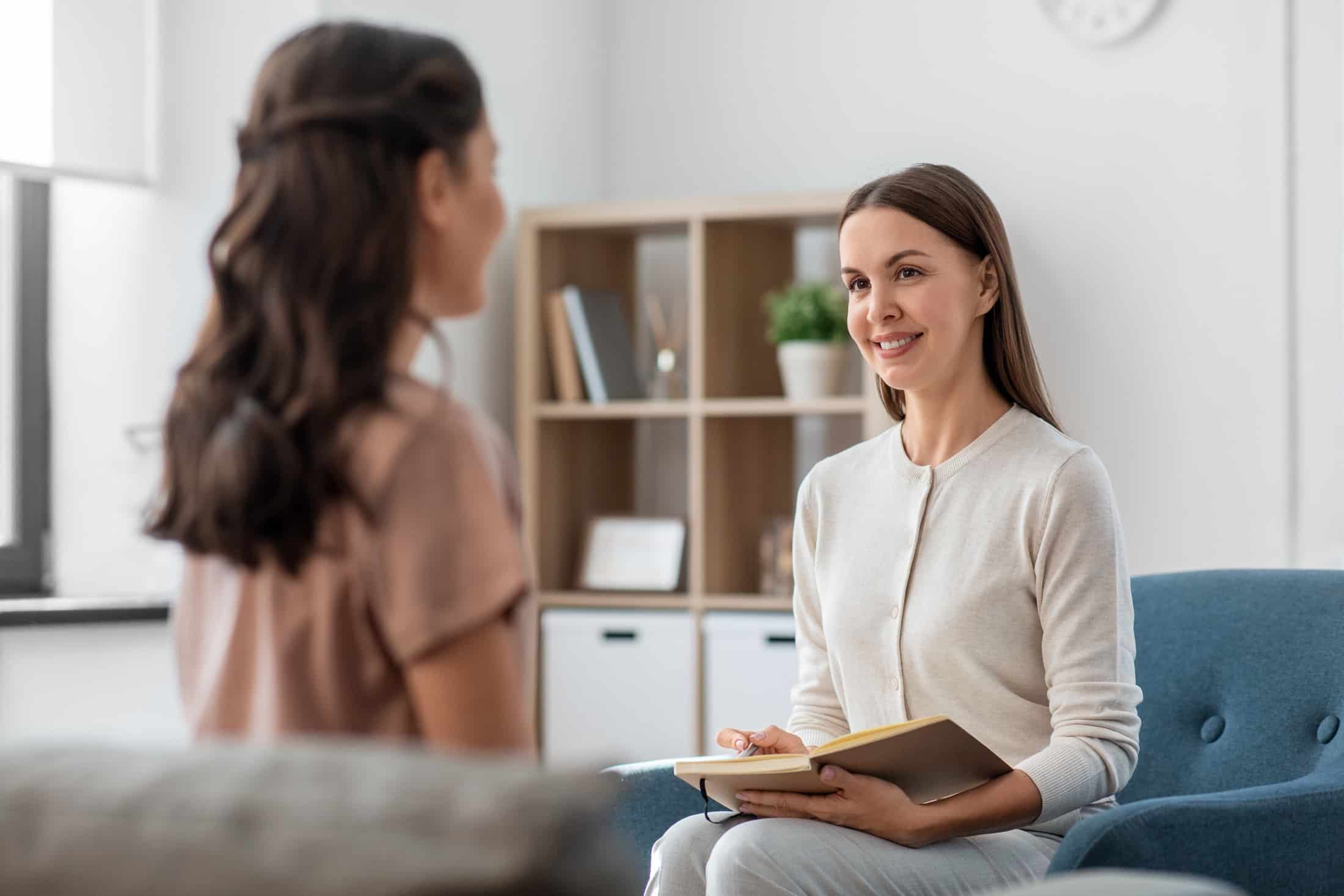 close up of 2 women sitting opposite each other in a meeting room