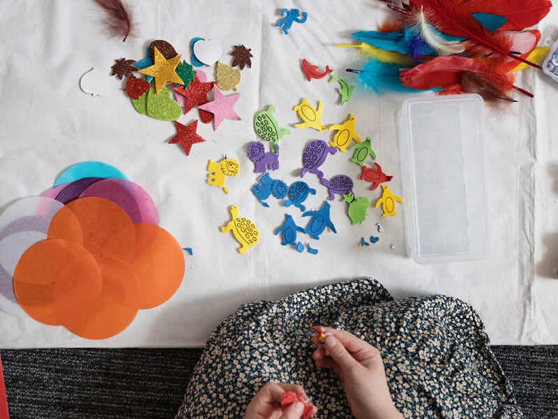 Top down view of child looking at play mat with lots of different arts and craft materials