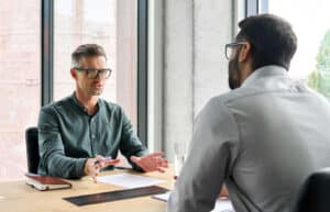 Two men sitting across a desk in conversation