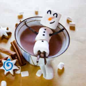 Marshmallow man sitting n top of a cup of hot chocolate